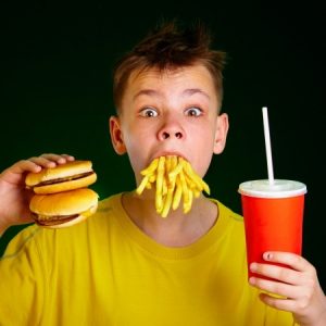 a young boy eating a fast food hamburger, french fries and a cola