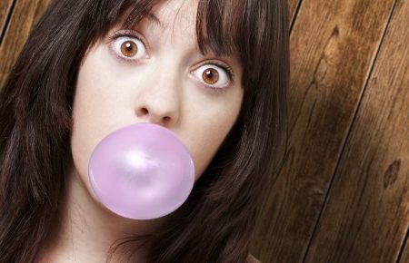 a young girl blowing a bubble with bubble gum