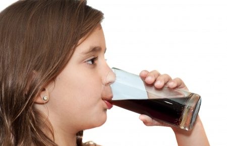 a young girl drinking a glass of cola