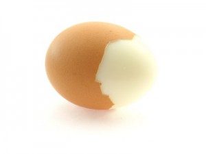 A hard boiled brown egg half shelled.