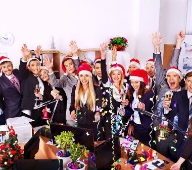 a Christmas party with a group of people waving at the camera