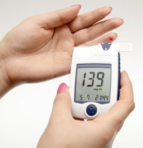 a female testing her blood suagr with a meter in her hands