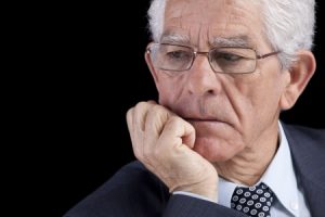 an older businessman with white hair leaning on his chin