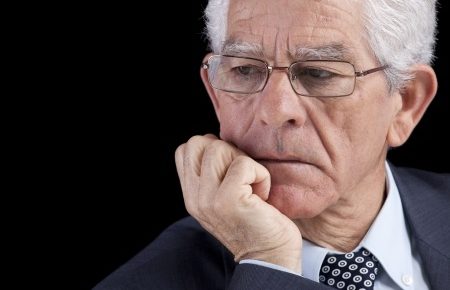 an older businessman with white hair leaning on his chin