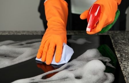 someone scrubbing their kitchen with orange rubber gloves on.