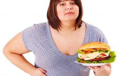 a fat girl holding a plate of food and holding her side in pain