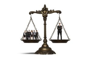 legal scales with a crowd on one side and one man on the other side