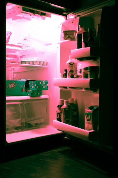 a refrigerator with an open door and pink light coming out