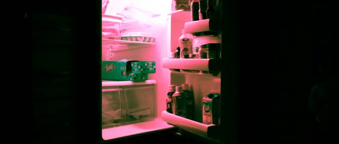a refrigerator with an open door and pink light coming out