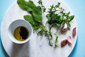 garlic, oregano and Italian herbs on a white cutting board