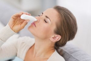 a young woman using nasal spray in her nose