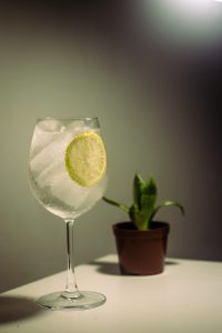 a long stemmed glas with gin and tonic with ice and a lime