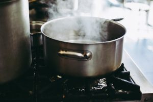 A stainless steel pan with boing water on the stove.