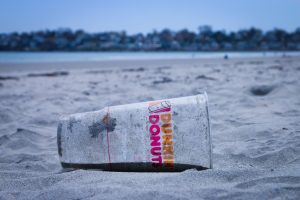 a plastic dunkin donut cup thrown on the beach