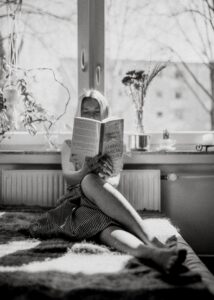 a girl reading a book sitting on her sofa
