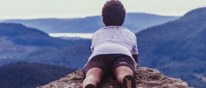 a woman laying on her stomach on a mountaintop