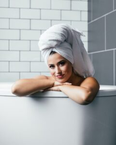 a beautiful woman in a bathtub with a towel on her head