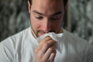 a man blowing his nose in a white tissue