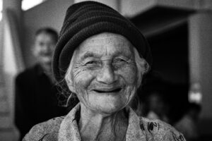 a smilng old woman wearing a black hat