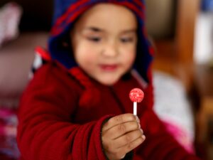 a young child smiling while he eats a lollipop