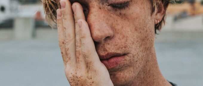 a young man with his hand on his face in stress