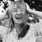 a laughing woman holding her hair