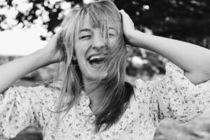 a laughing woman holding her hair