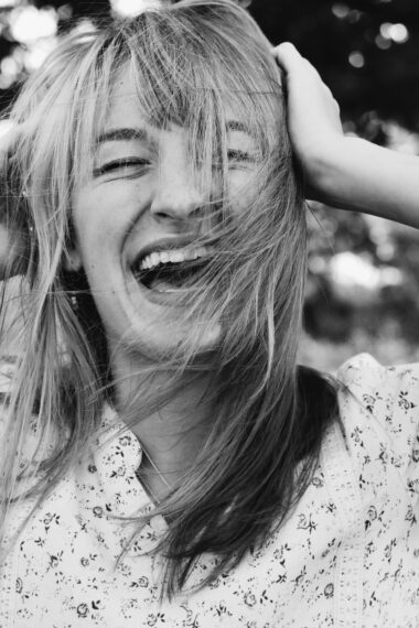 a laughing woman holding her hair