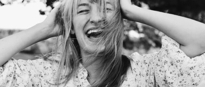 a laughing woman holding her hair