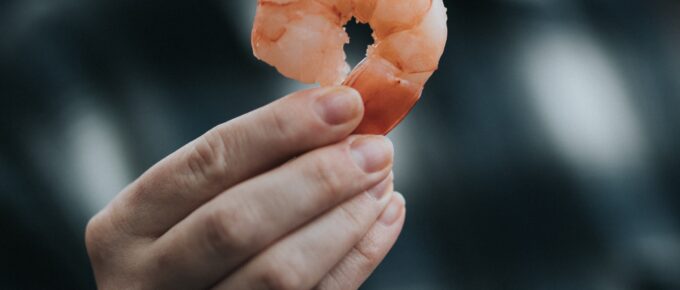 a woman holding a shelled shrimp