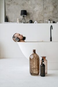 a bearded man relaxing in a clawfoot bathtub listening to music