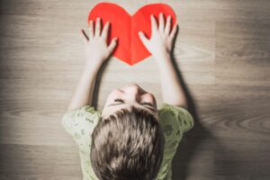 a small child with his hands on a drawn red heart